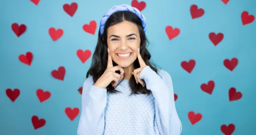 Valentines Image of girl showing her teeth after undergoing a teeth whitening procedure with a blue background with red hearts