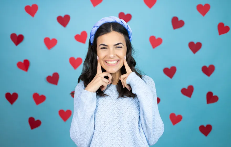 Valentines Image of girl showing her teeth after undergoing a teeth whitening procedure with a blue background with red hearts